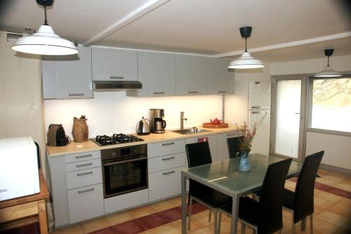 une cuisine avec des armoires blanches et une table avec des chaises dans l'établissement La Petite maison-Caluire 45 m2, à Rillieux-la-Pape