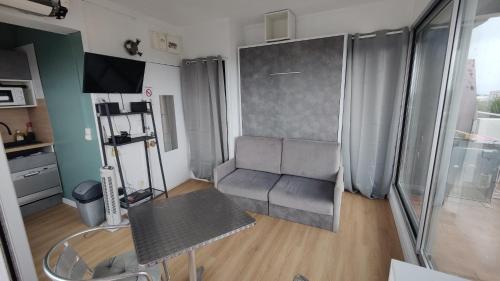 a living room with a couch and a table at Studio vue panoramique-centre ville in La Grande-Motte