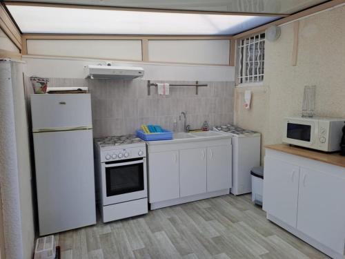Elle comprend une petite cuisine équipée d'appareils électroménagers blancs et d'un évier. dans l'établissement Location vacances, à La Bernerie-en-Retz