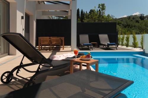 a patio with a chair and a table next to a swimming pool at Anapnoe ikies Corfu Adults Friendly in Sfakerá