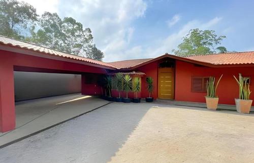 a red house with a yellow door and some plants at Casa ampla e confortável in Cotia