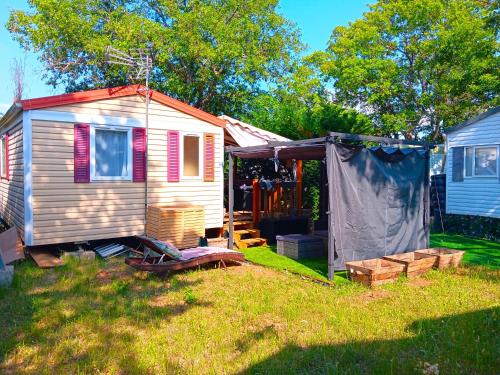 a tiny house in a yard next to a house at MOBILHOME 4 places in Sainte-Croix-de-Verdon