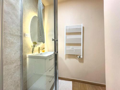 La salle de bains est pourvue d'un lavabo et d'une porte de douche en verre. dans l'établissement Nid douillet au cœur de Lyon, à Lyon