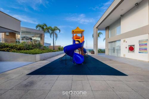 a blue slide in front of a building at Condomínio a beira-mar c/ piscina - SHC in Piçarras