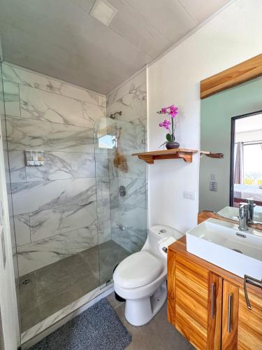 a bathroom with a shower and a toilet and a sink at Canavida Villas & Resort in Uvita