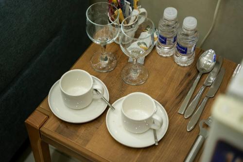 een tafel met twee kopjes en borden en wijnglazen bij شقق قلب العاصمة in Bagdad