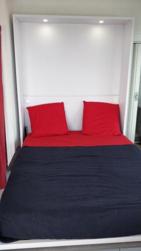 - un lit avec 2 oreillers rouges dans l'établissement Studio vue panoramique-centre ville, à La Grande Motte
