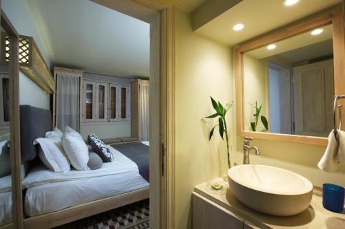 a bathroom with a bed and a sink and a mirror at Dar Alma in Soûr