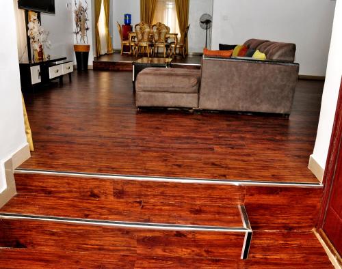 a living room with a couch and a wooden floor at Crosswater Lodge Abuja - Short Let & Luxury Apartment in Kubwa