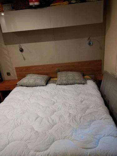un grand lit blanc avec deux oreillers dessus dans l'établissement Mobil home camping 5 étoiles, à Puget-sur Argens