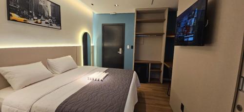 a bedroom with a large bed with a tv on the wall at Blue Inn Hotel in Boa Vista