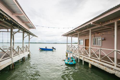 two boats in the water next to a house at La Caribena Beach House- Bocas del Toro, Isla Colón, Panamá in Big Creek