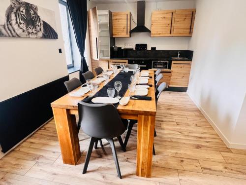 un lungo tavolo in legno in una cucina con sedie di Duplex cosy proche Gérardmer a Le Tholy