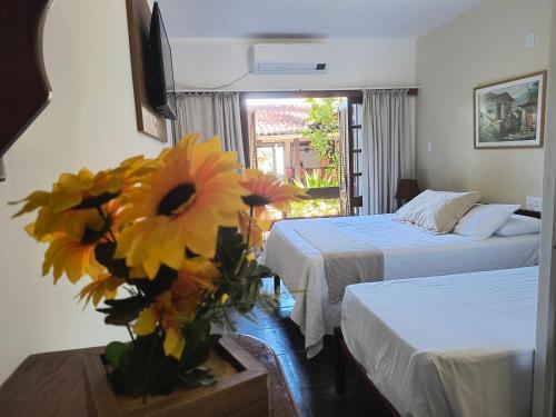 a hotel room with two beds and a vase of flowers at Pousada Guaratiba in Prado