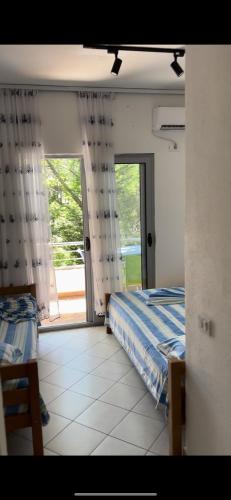 a bedroom with two beds and a door to a patio at Hotel PEJA in Velipojë
