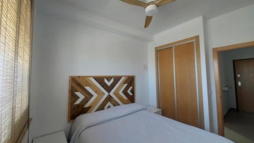 a bedroom with a bed with a wooden head board at Este in La Playa de la Torre de Piles