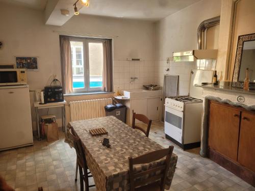 - une cuisine avec une table, des chaises et une cuisinière dans l'établissement Maison simple et ancienne 