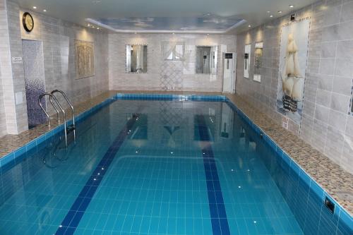 a large swimming pool with blue tiles in a building at Barbaris in Birobidzhan