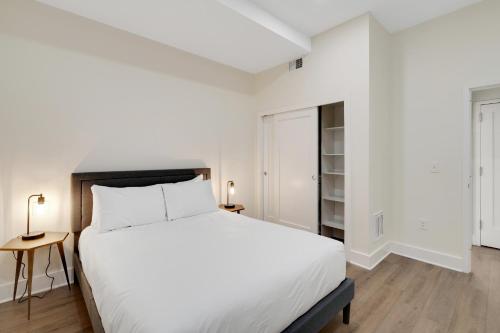 a white bedroom with a large bed and a table at The Ledger Residences by Sosuite - Old City in Philadelphia