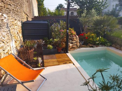 une piscine avec une chaise orange et une terrasse et une piscineituresitures dans l'établissement Le paradis caché, à Chervettes