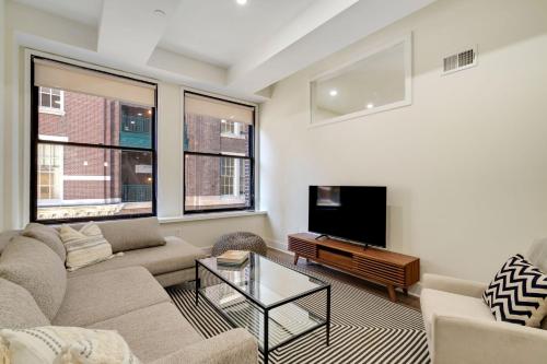 a living room with a couch and a tv at The Ledger Residences by Sosuite - Old City in Philadelphia