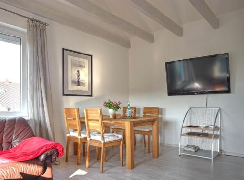 a living room with a table and a tv on the wall at Ferienwohnung Relax nähe Herzzentrum in Bad Oeynhausen