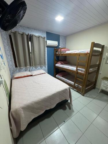 a room with a bed and bunk beds in it at Hostel Casa Jambo Guaruja in Guarujá