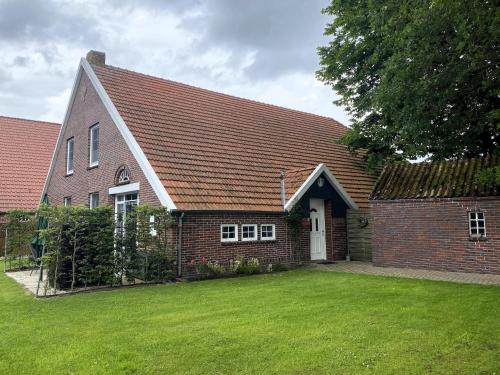 a brick house with a grass yard in front of it at Reihenhäuser in Strackholt in Strackholt