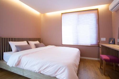 a bedroom with a large white bed and a window at Puzzlestay House in Seoul