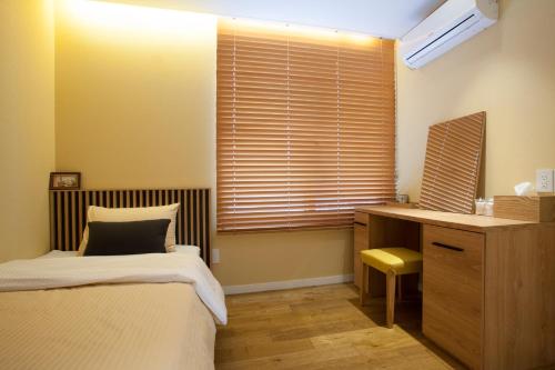a bedroom with a bed and a desk and a window at Puzzlestay House in Seoul