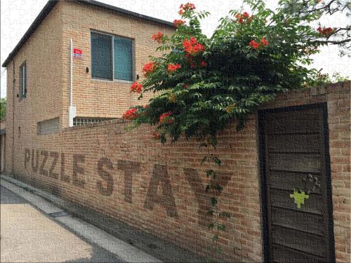 a brick wall with a door and a plant with red flowers at Puzzlestay House in Seoul