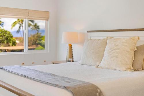 a white bedroom with a bed and a window at Puamana 111-2 Superior Ocean View in Lahaina