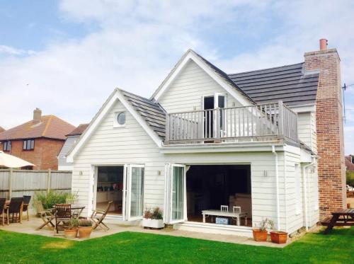 a white house with a balcony and a patio at 5 Bedroom Family Friendly Beach House - a skip to the water! in West Wittering