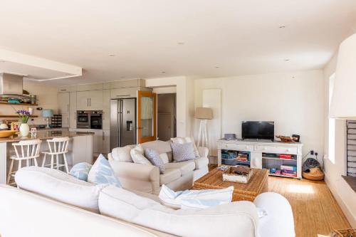 a living room with white furniture and a kitchen at 5 Bedroom Family Friendly Beach House - a skip to the water! in West Wittering