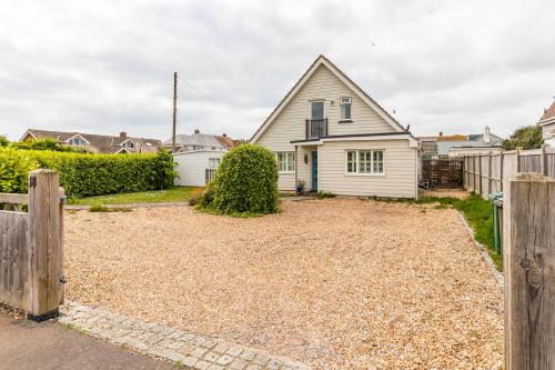 a white house with a fence and a yard at 5 Bedroom Family Friendly Beach House - a skip to the water! in West Wittering