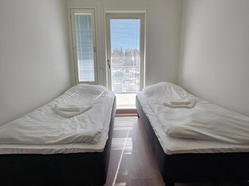 due letti in una stanza con una finestra di Heim Apartments - Rivitalo a Seinäjoki