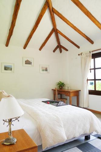 a bedroom with a white bed with a table and a window at Hotel Claroscuro Casa Ilayaku in Guangopolo