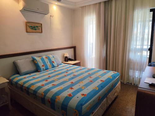 a bedroom with a large bed with a blue comforter at Apartamento Aquaville Pé na areia e Água coco in Aquiraz