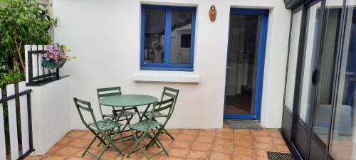 une table et des chaises assises sur une terrasse dans l'établissement Charmante maison proche de la mer à Locquémeau, à Locquémeau