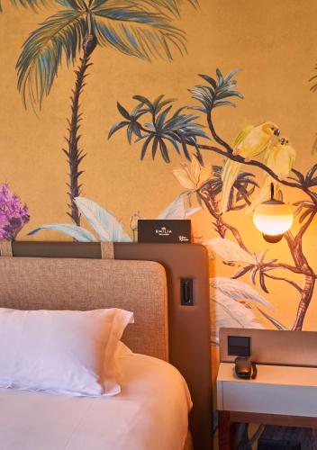 a bedroom with a painting of palm trees on the wall at Hotel Villa Emilia in Barcelona