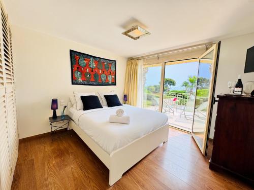 une chambre avec un grand lit blanc et un balcon dans l'établissement Sublime villa with sea view in Cap d'Antibes, 500 m from the beach, à Antibes