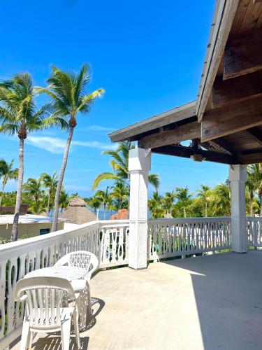 a deck with two white chairs and palm trees at Coconut Cove Resort & Marina in Islamorada