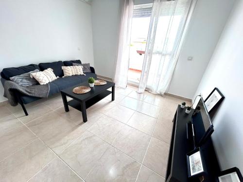 een woonkamer met een blauwe bank en een tafel bij Apartamento Empul Rota Príncipe in Rota