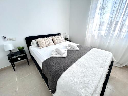 een slaapkamer met een bed met witte lakens en een raam bij Apartamento Empul Rota Príncipe in Rota