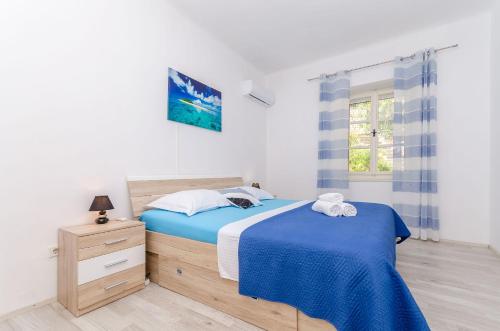 a bedroom with a blue bed and a window at Apartment Kokic in Zastražišće