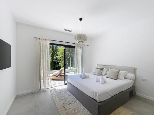 Un dormitorio blanco con una cama y una ventana grande. en Villa Manon, en Le Rouret