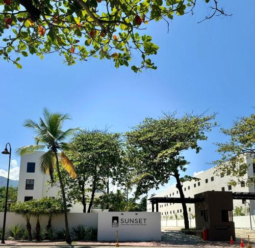 a sign in front of a building with a palm tree at Escapada perfecta, apartamento frente al mar in San Felipe de Puerto Plata