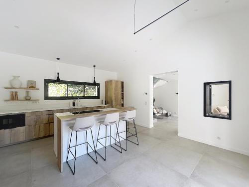 cocina con paredes blancas y encimera con taburetes en Villa Manon, en Le Rouret