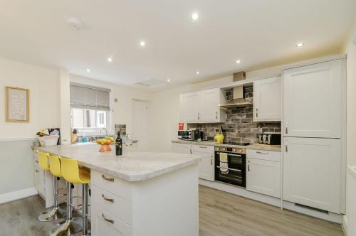 a kitchen with white cabinets and yellow bar stools at Roseberry House in Guisborough