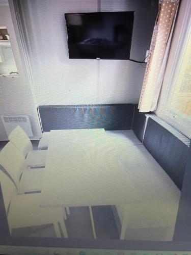 Cette chambre dispose d'une table, d'un canapé et d'une télévision. dans l'établissement Au Paradis, à Saint-Paul-lès-Dax